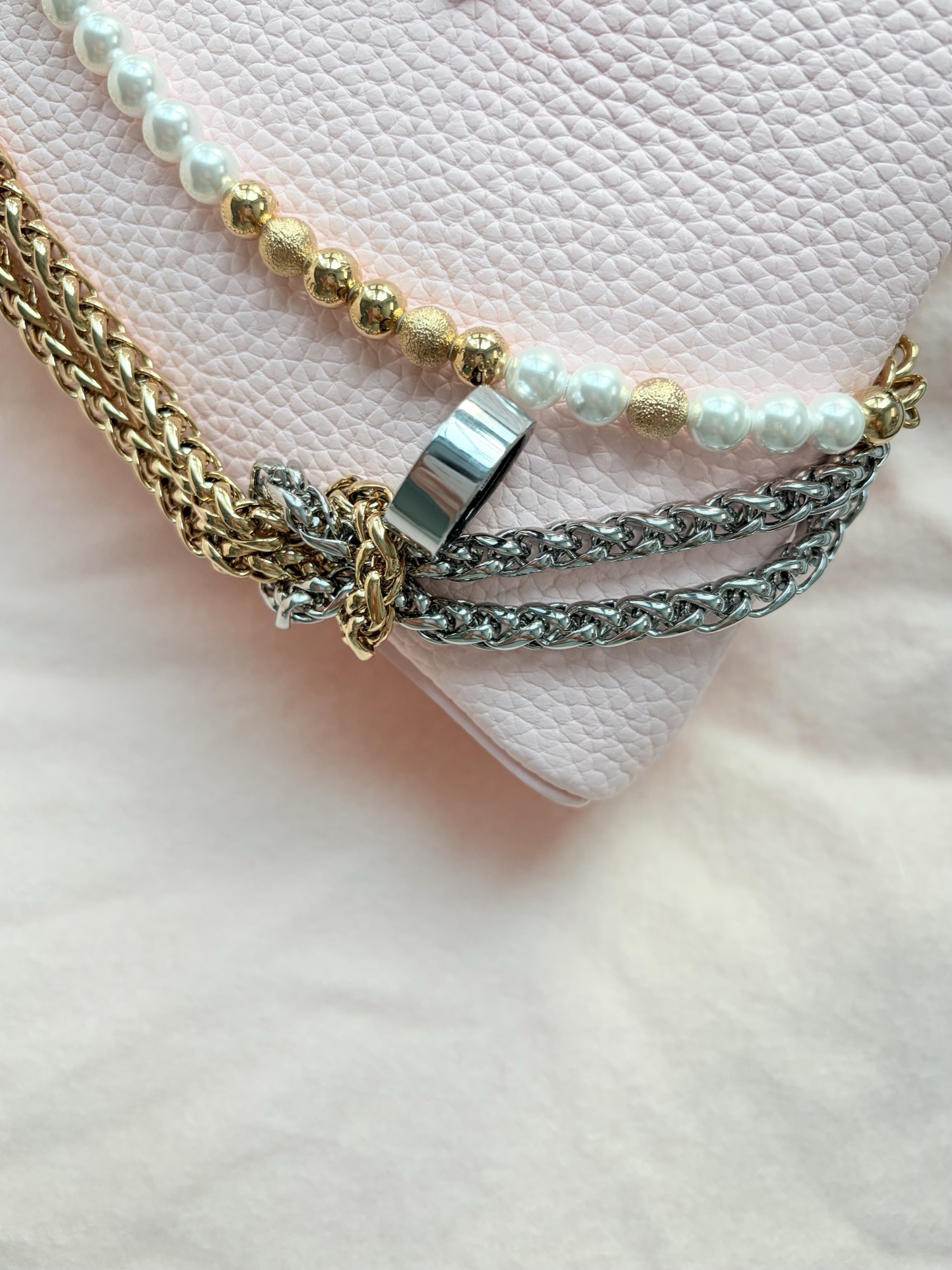 Silver Soul Vibe Ring photographed with chains and pearls on a blush bag
